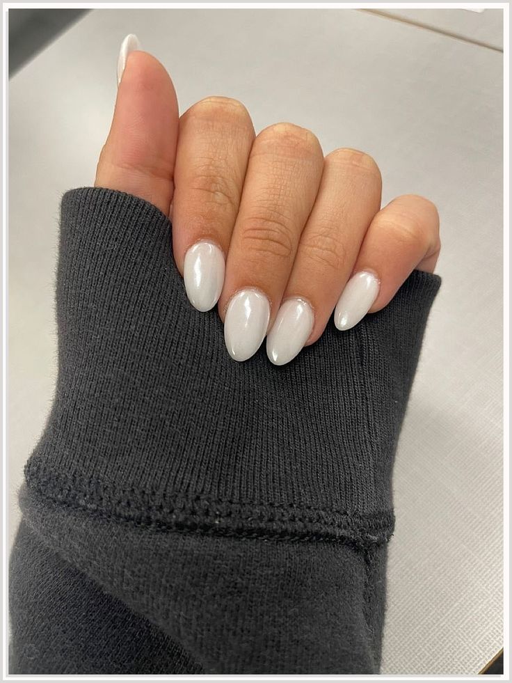 Glossy White Almond-Shaped Nails: A Chic Contrast with Cozy Grey Sweater for Effortless Style.