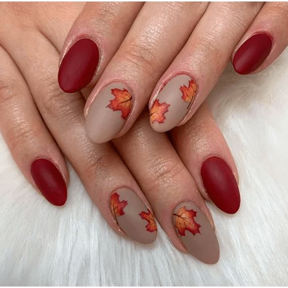 Elegant Autumn-Inspired Nail Design with Deep Red and Soft Beige Tones, Featuring Accent Nails with Vibrant Leaves and a Matte Finish.