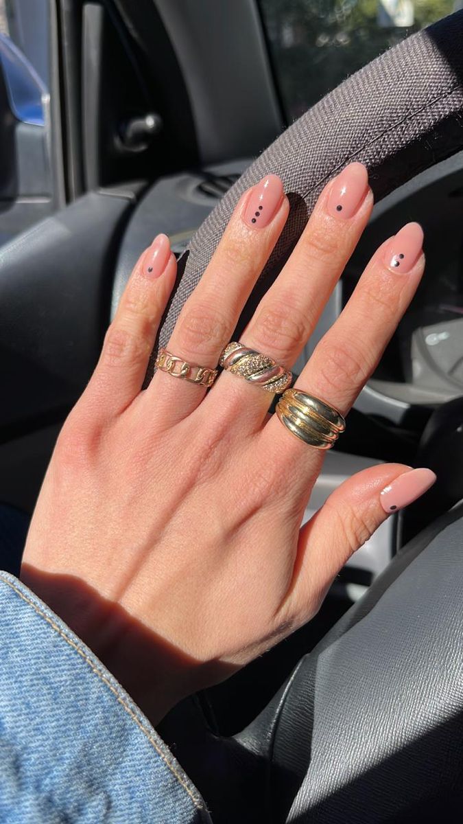 Chic Blush Pink Nail Design with Black Dots and Gold Ring Accents.