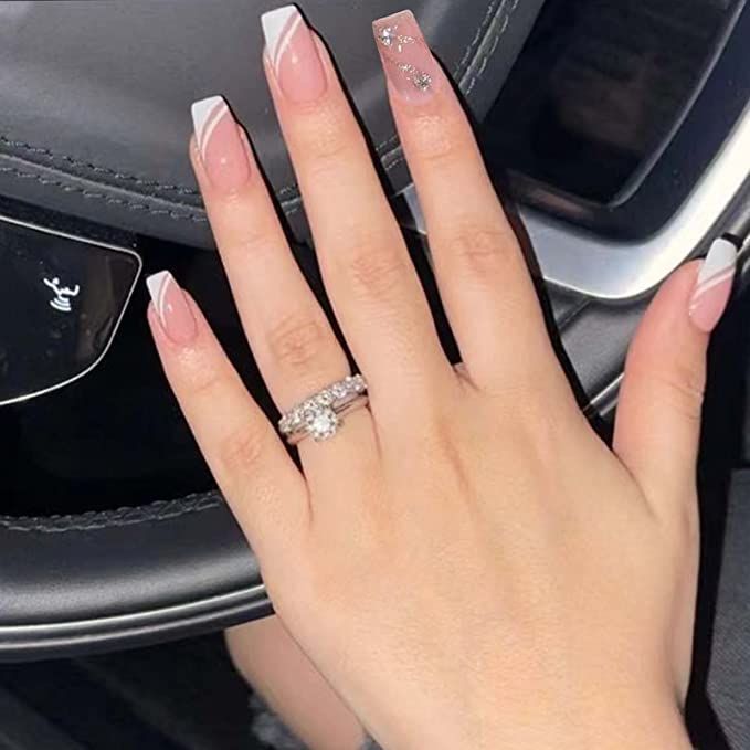 Chic French Tip Nail Design with Soft Pink Base and Glamorous Accent Stones.