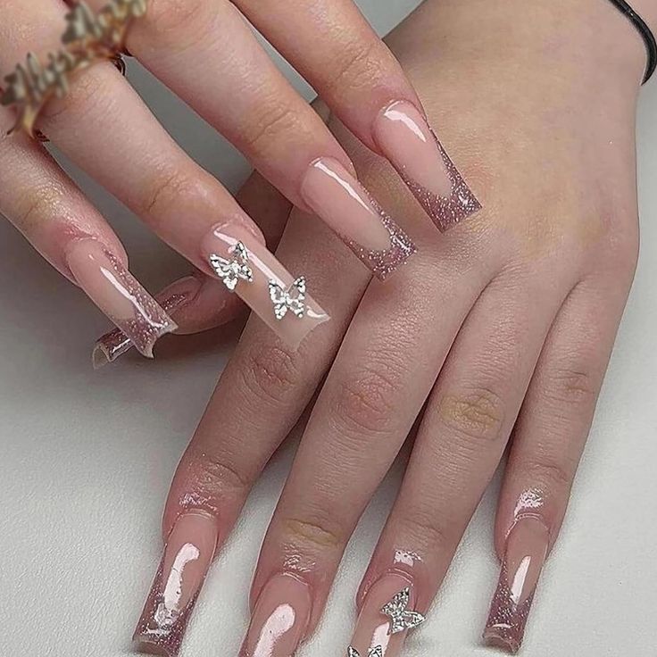 Elegant Acrylic Nail Design with Nude and Glitter Accents Enhanced by Whimsical Butterfly Decor