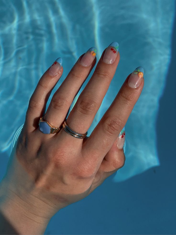 Playful Pastel Nail Art with Light Blue French Tips and Cheerful Floral Accents.