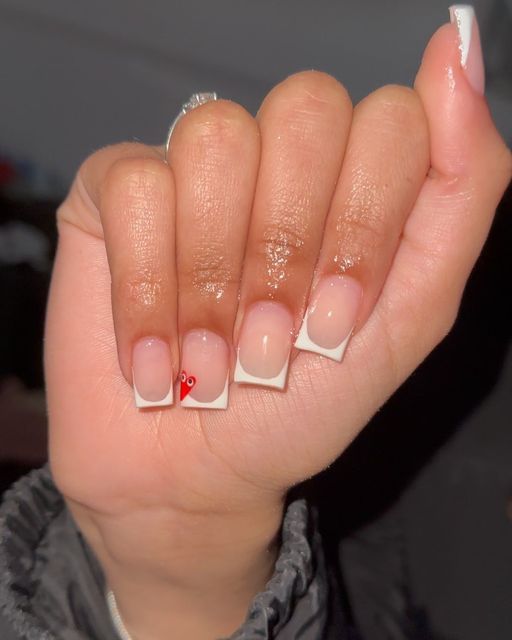 Elegant French Manicure with a Modern Twist and Playful Red Accent.