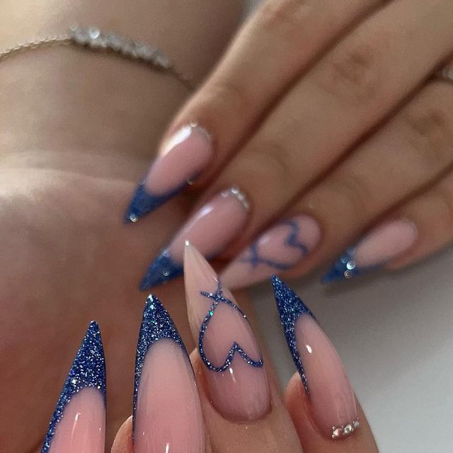 Bold Elegance: Glittery Blue Ombre Stiletto Nails with Playful Heart Accents.