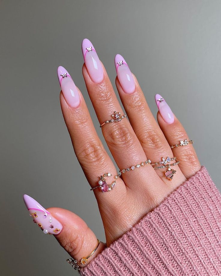 Chic Long Pink Nails with Embellishments and Dainty Rings.