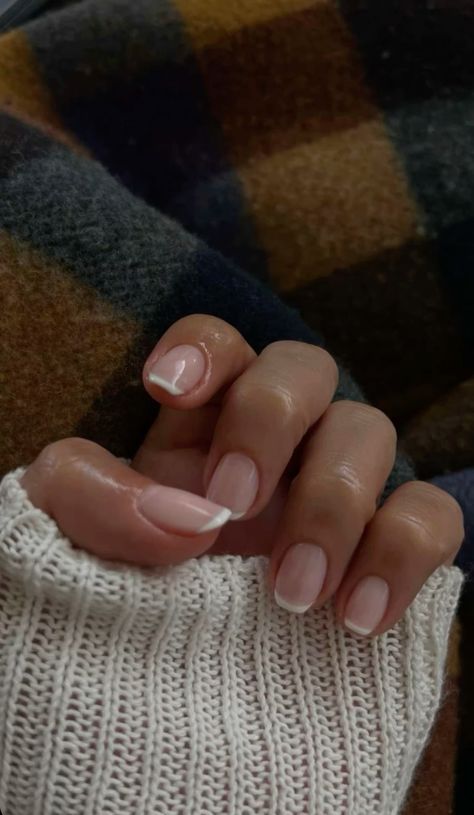 Sophisticated Elegant Nude Manicure with Subtle White Tips and Cozy Background.