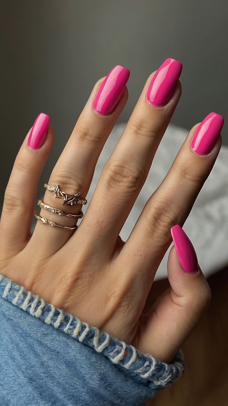 Elegant Vibrant Pink Nail Design with Glossy Finish and Gold Ring Accents.