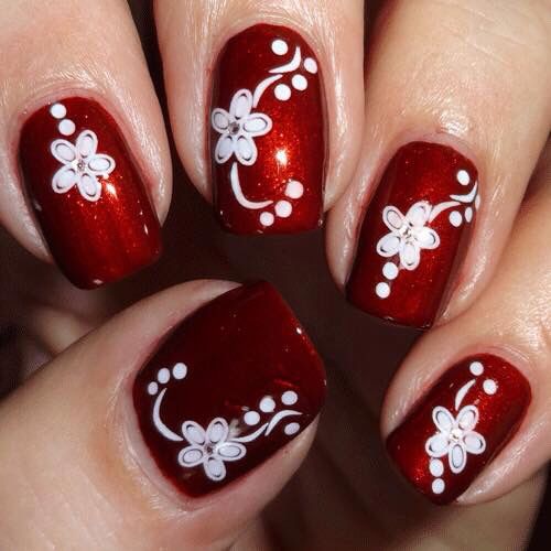 Elegant Shimmering Red Nails with Delicate White Floral Designs.