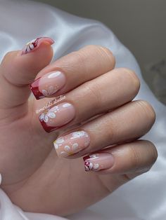 Modern Floral Nail Art: Nude Base with Bold Red Tips and Artistic Floral Accents.