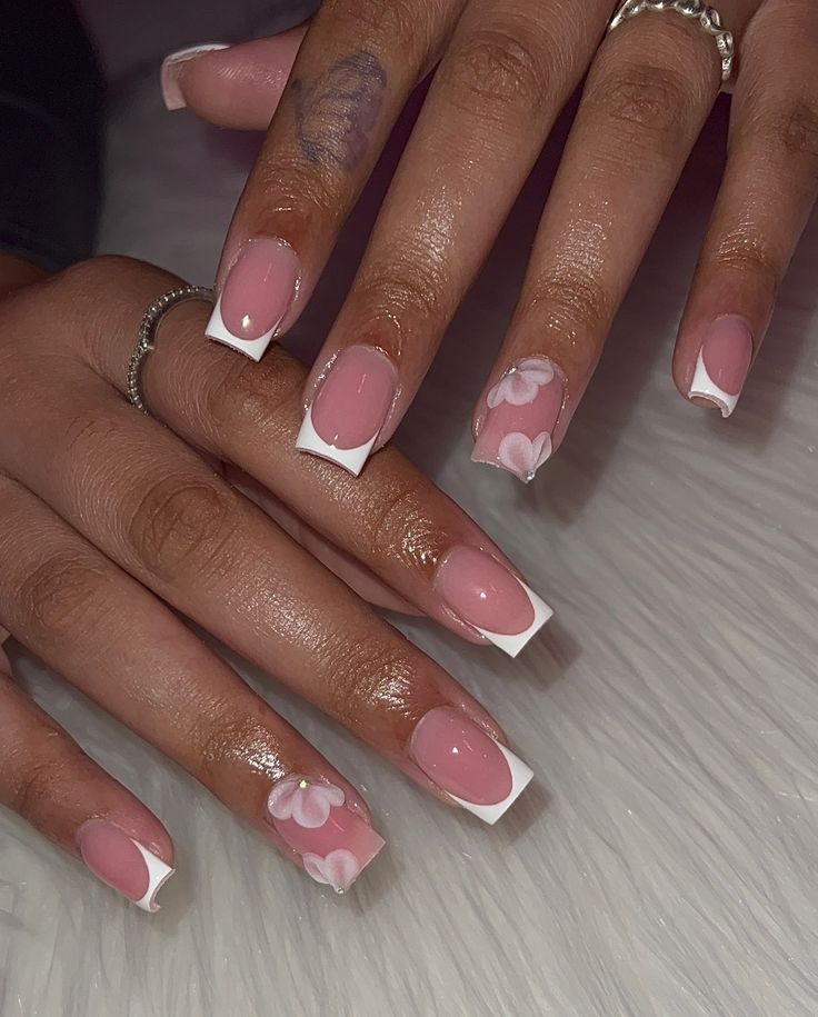 Chic Floral Nail Art: Soft Pink Base with Elegant White French Tips and Intricate Flower Designs.