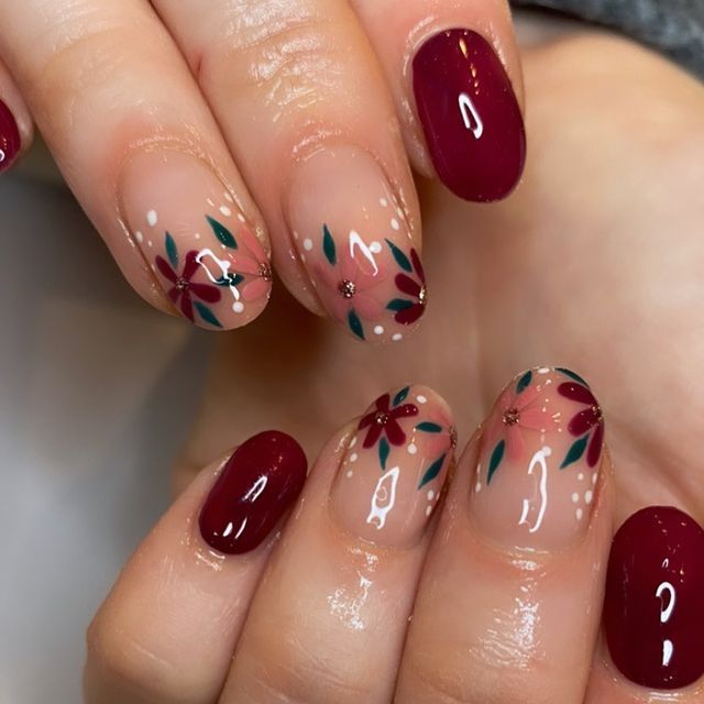 Sophisticated Nail Design: Deep Burgundy and Nude with Floral Accents and Gem Highlights.