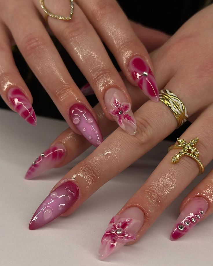 Whimsical Elegant Nail Design: Shades of Pink with Intricate Floral Patterns and Dramatic Pointed Tips.