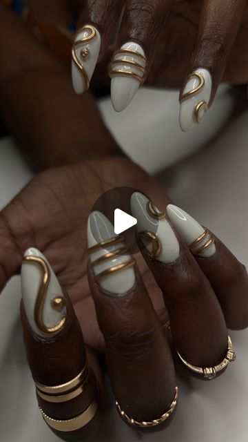 Sophisticated Almond-Shaped Nail Design with Elegant White Polish and Intricate Gold Swirls