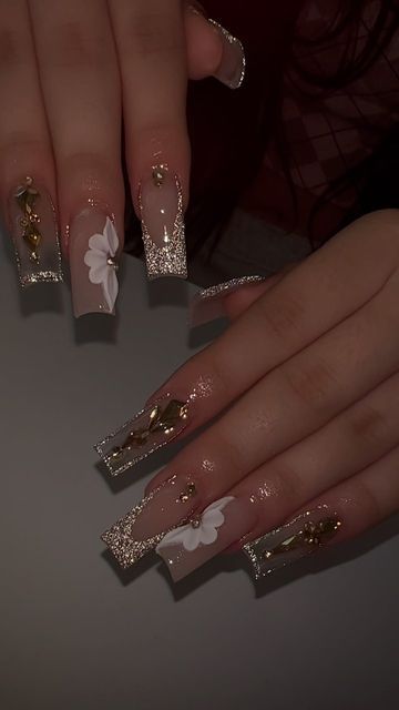 Elegant Acrylic Nails: Nude Base with Intricate Floral Designs and Glamorous Gold Accents.