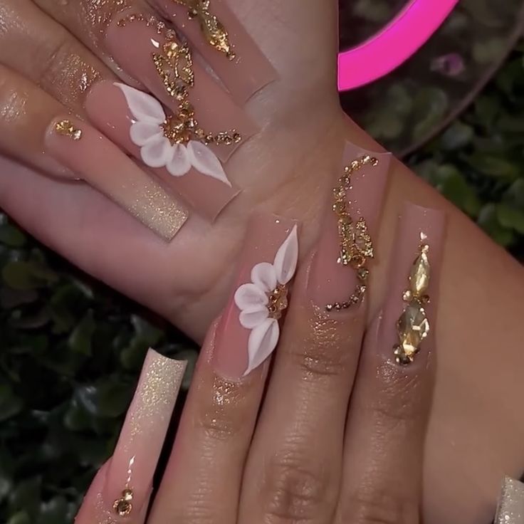 Sophisticated Nude Nail Design with Gold Leaf, Gems, and Bold Floral Accents.