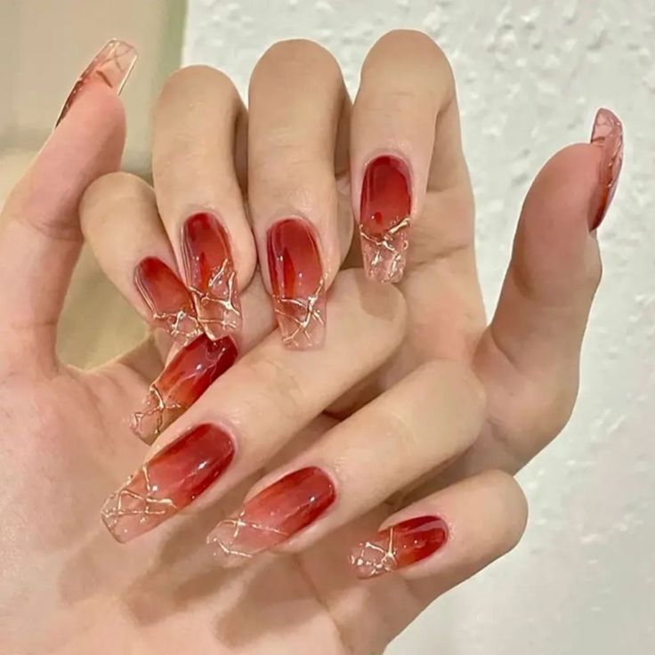 Sophisticated Ombre Nail Design: Deep Red to Translucent Tips with Intricate Gold Accents