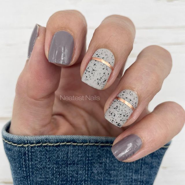 Chic Muted Gray and Beige Nail Design with Speckled Pattern and Metallic Accents.