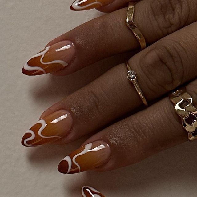 Chic Elongated Nails with Warm Brown-Cream Gradient and Playful White Swirls.