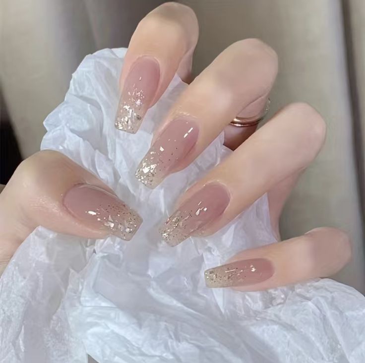 Sophisticated Nude Nails with Sparkling Gold Tips and Glamorous Glitter Accents.