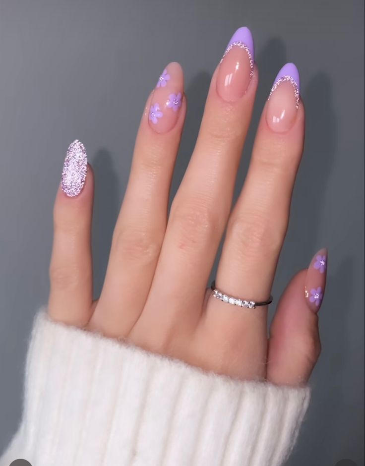 Charming Pastel Purple and Nude Nail Design with Floral Patterns and Glitter Accents.