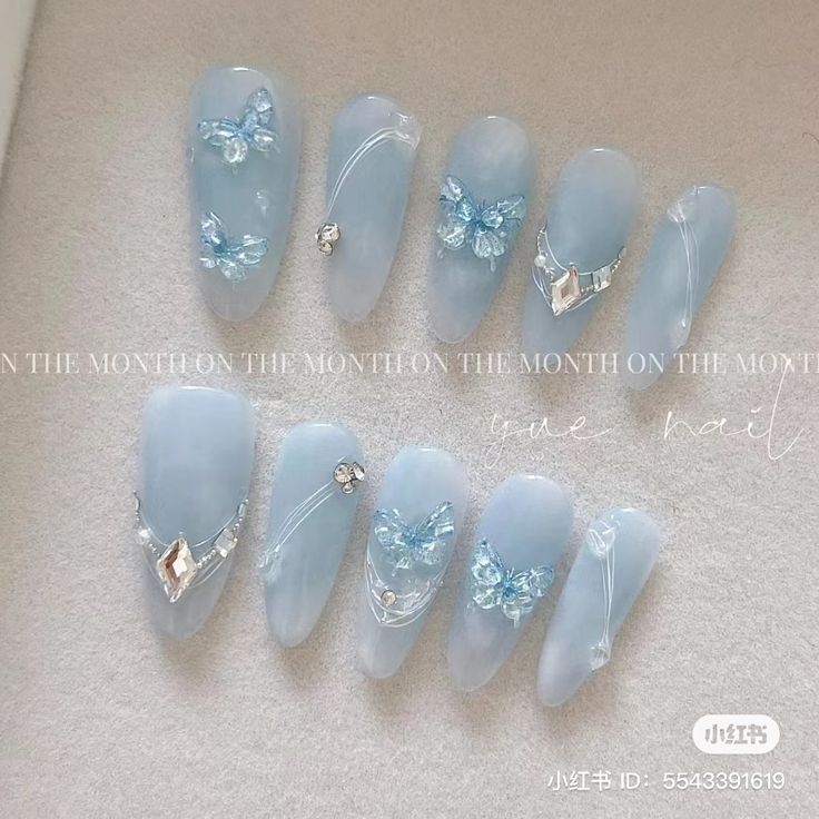 Elegant Delicate Blue Nail Design with Floral Accents and Gemstone Details.