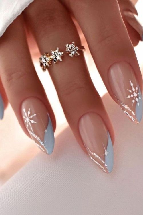 Whimsical Winter-Inspired Nail Design: Pastel Blue Tips, Nude Base, and Glittery Snowflake Accents