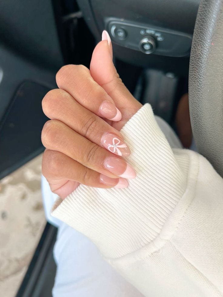 Sophisticated Nail Design: Subtle French Tips with Charming Bow Accents.