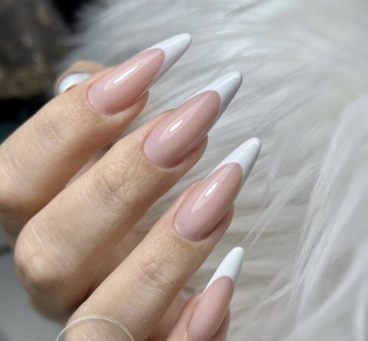 Chic Almond-Shaped Nail Design with Soft Nude and Sharp White Tips.