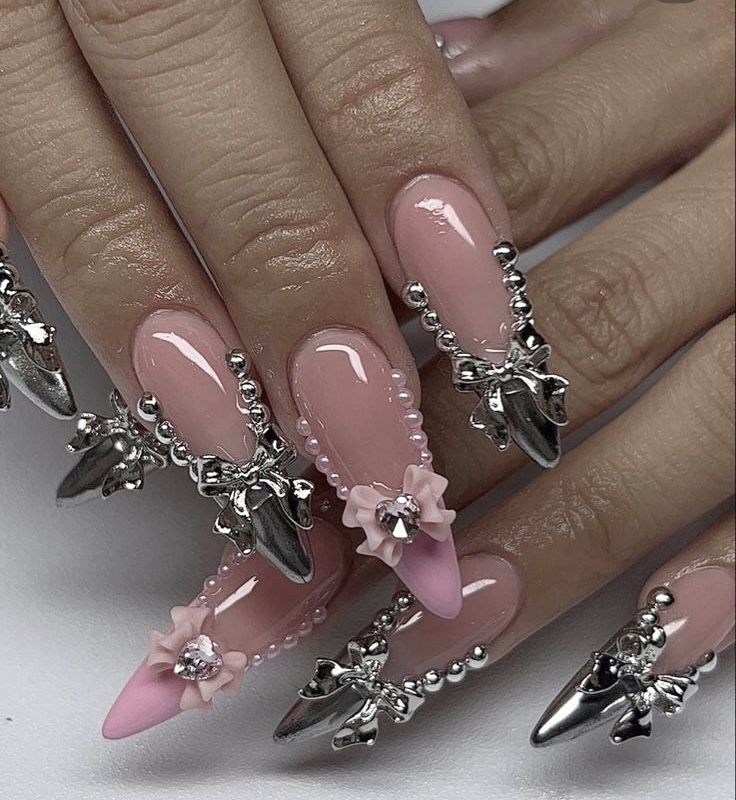 Luxurious Nail Art: Soft Pink Hues with Metallic Accents and Floral Embellishments.