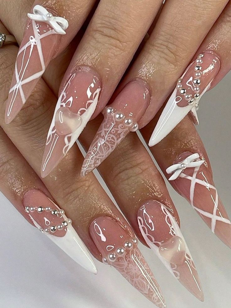 Chic Stiletto Nails with Intricate Designs in Nude and White.