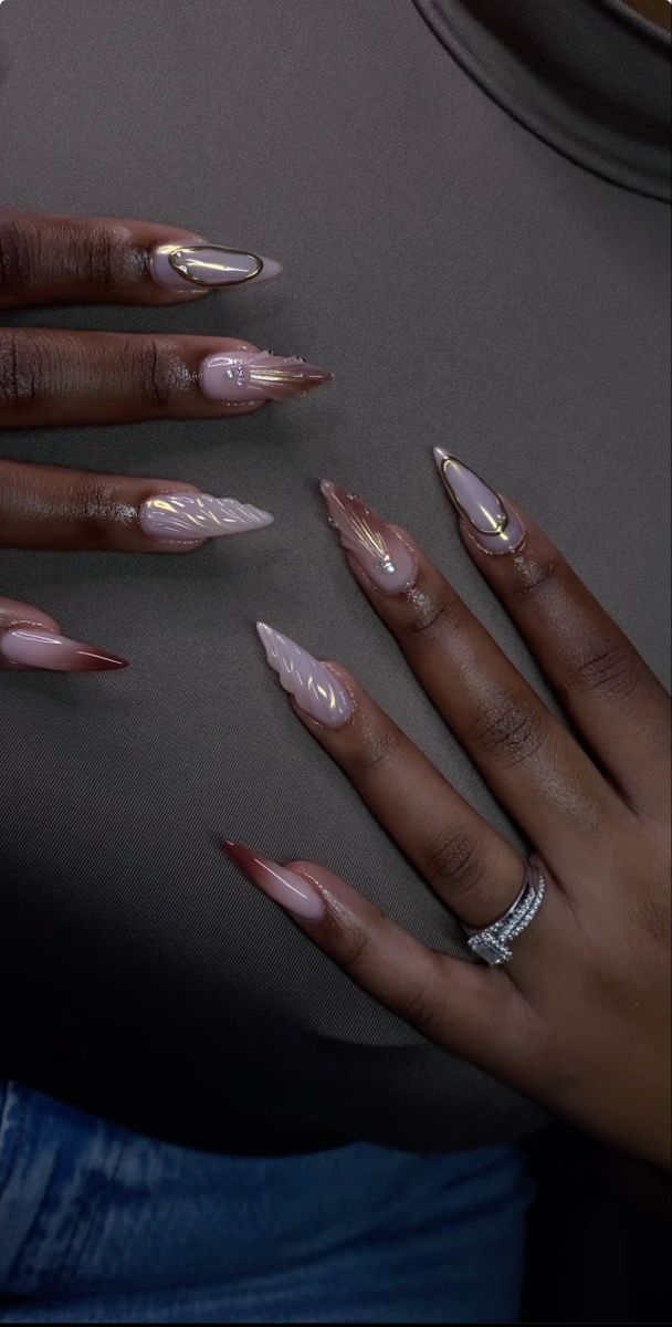 Sophisticated Nude and Burgundy Nail Design with Gold Accents and Textured Leaf Pattern.