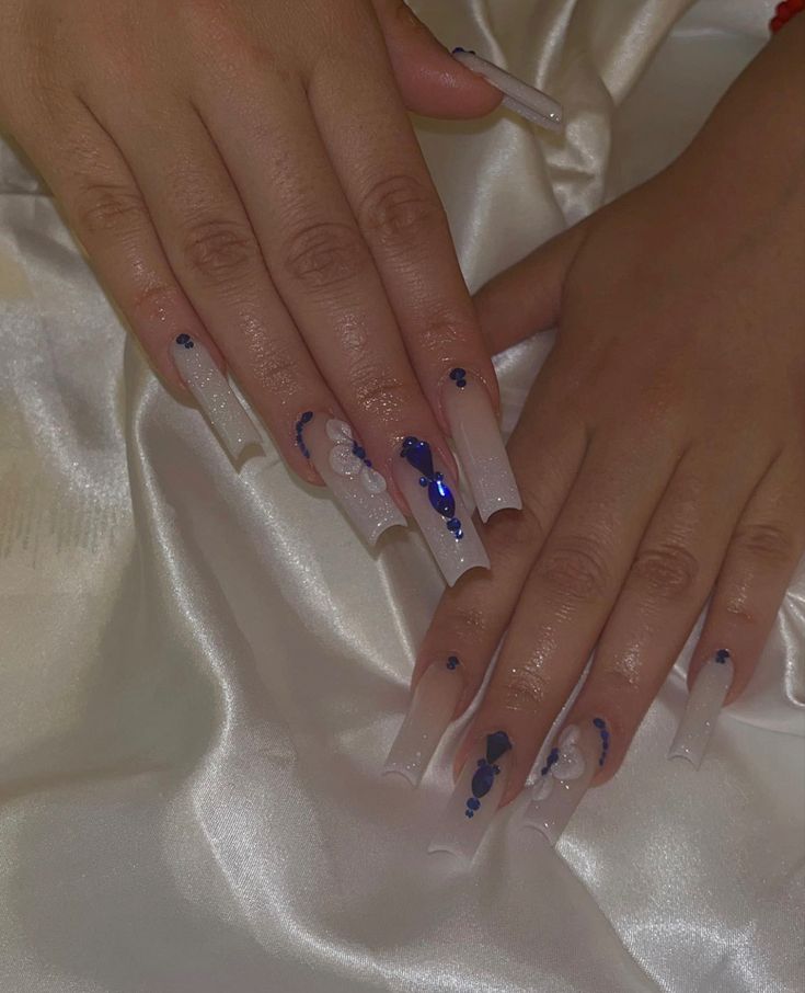 Elegant Soft Nude Acrylic Nails with Intricate Blue and White Designs for Any Special Occasion.