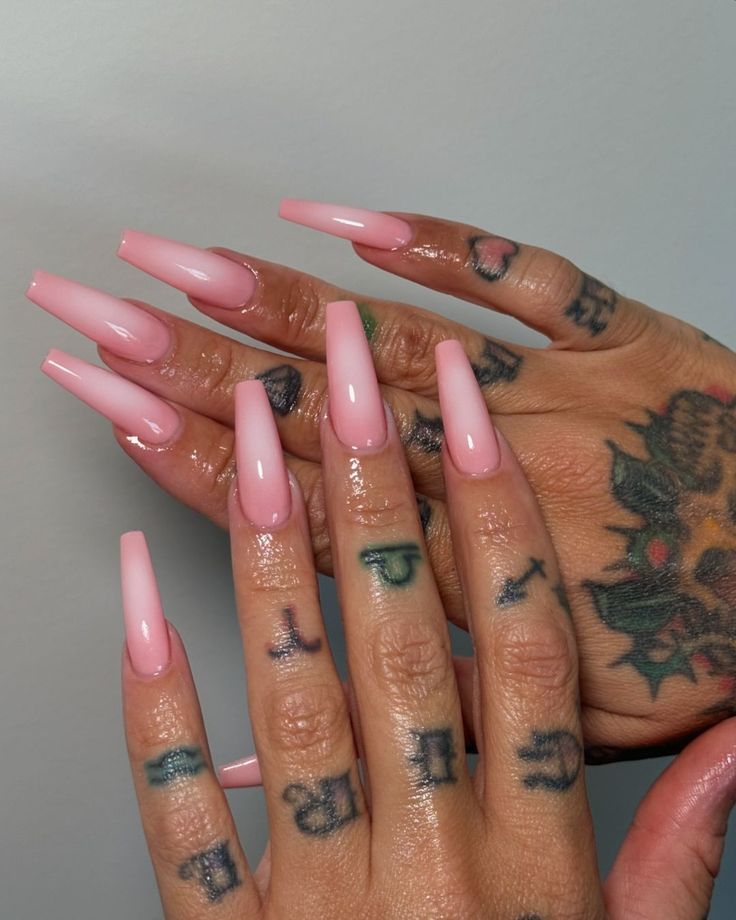 Elegant Long Pink Nails with Glossy Finish and Intricate Tattoos for a Chic Look.