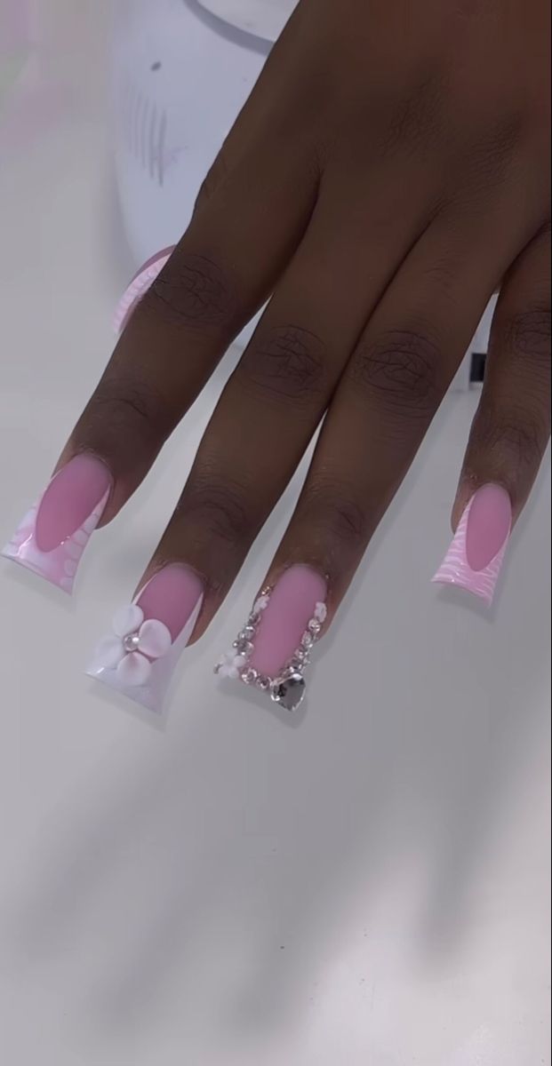 Chic Glamorous Nail Design: Soft Pink and Clear Elegance with Floral Accents and Sparkling Gems.