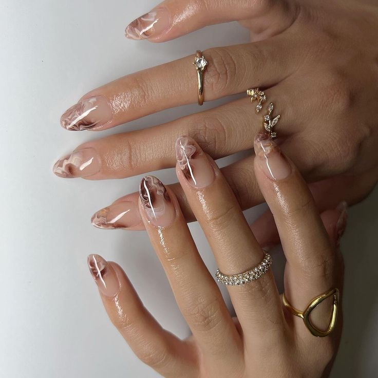 Sophisticated Nail Design: Translucent Marble Patterns with Glossy Finish and Delicate Accessories.