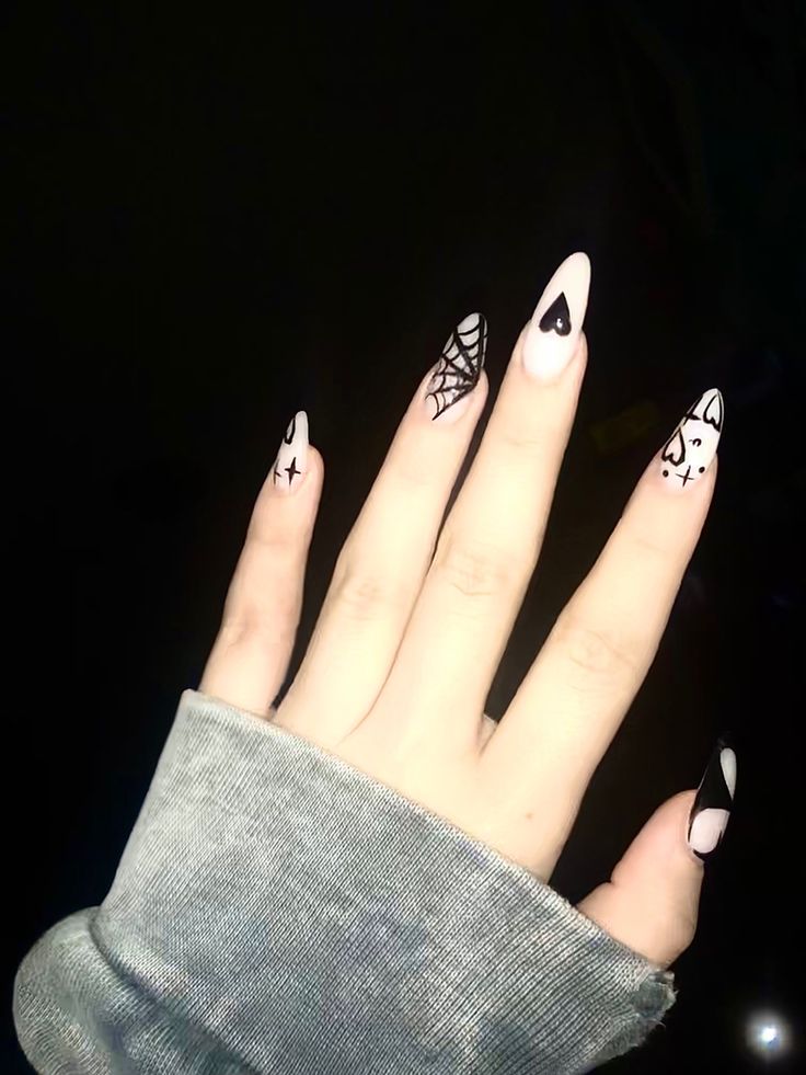 Chic Nail Art: Bold Elongated Shapes with Whimsical Patterns in Soft Pink and Black.