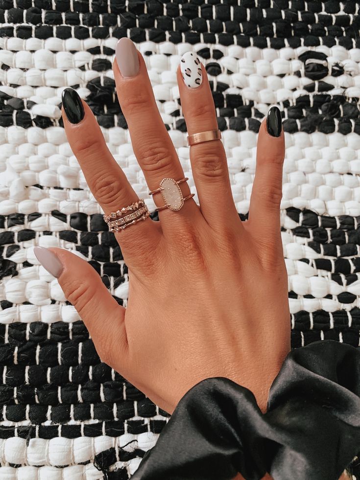 Chic Nail Design: Matte Black and Soft Gray with Playful Dalmatian Accent and Delicate Rings.