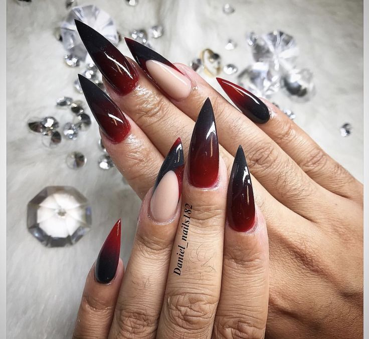 Dramatic Stiletto Nails with Gradient Red and Black, Elegant Nude Accent, and Sparkling Crystals.