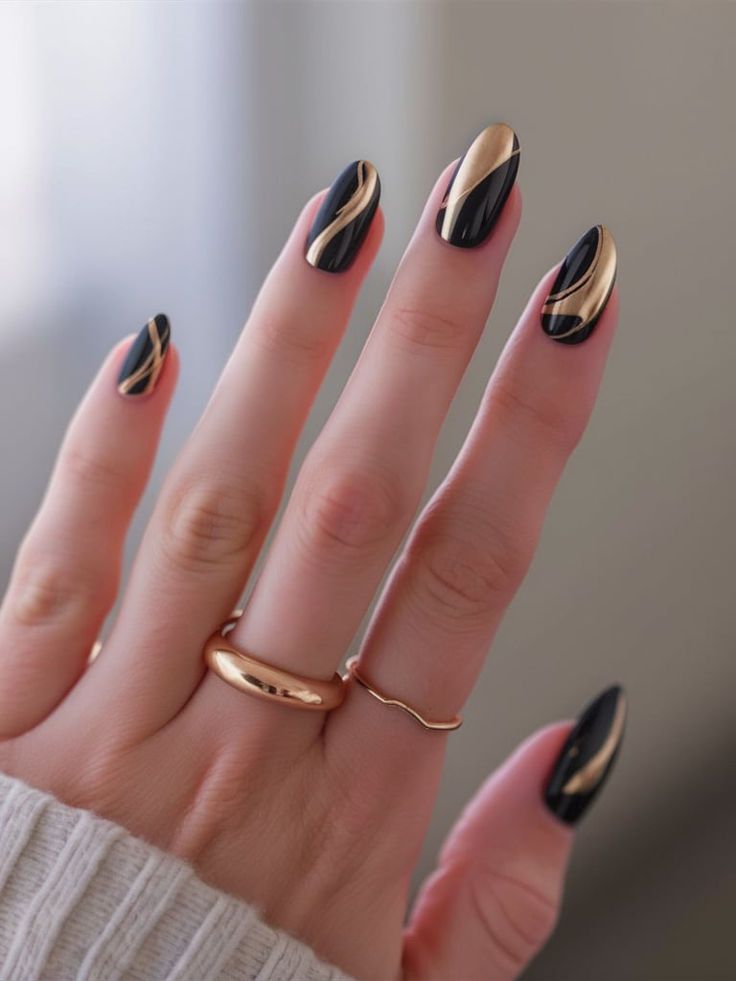 Elegant Chic Black and Gold Nail Design with Elongated Tips and Glossy Finish.