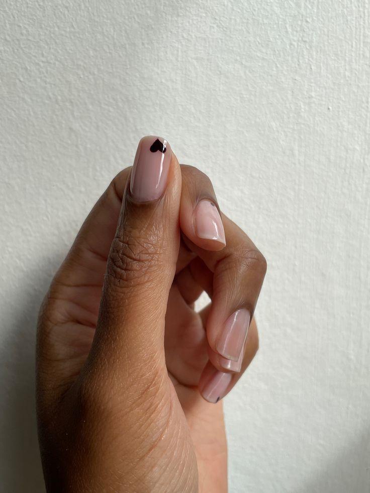 Chic Minimalist Nail Design: Soft Nude Base with Playful Black Heart Accent