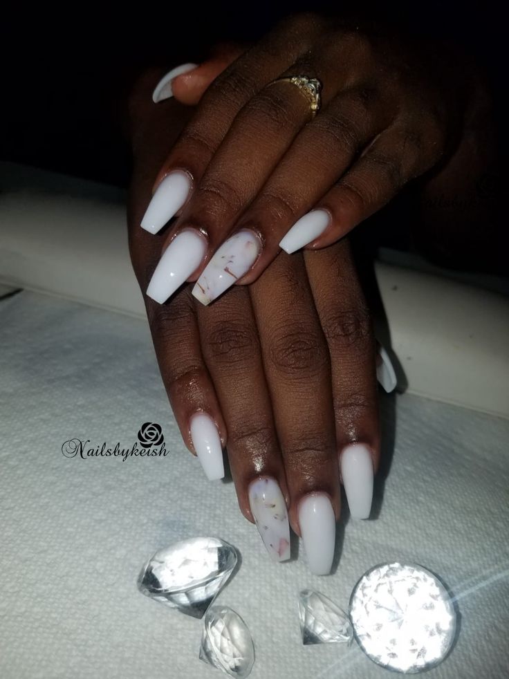 Sophisticated Glossy White Nail Design with Unique Marble Accents and Sparkling Gem Accessories.