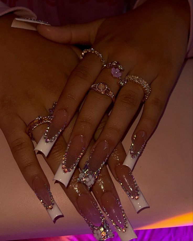 Glamorous Long Nails with Clear and White Tips, Rhinestones, and Elegant Nail Art Accented by Chic Rings.