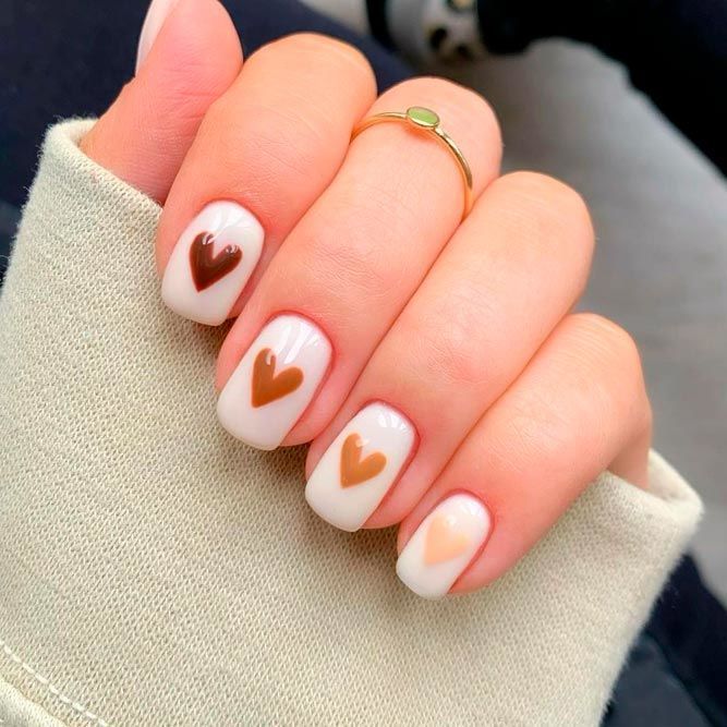 Elegant Heart-Shaped Nail Design in Brown and Neutral Hues on White Background.