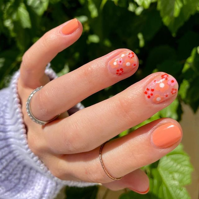 Charming Coral Nail Design with Whimsical Floral Accents for a Cheerful Spring Aesthetic.