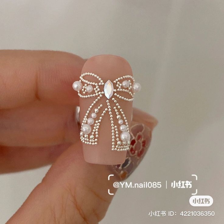 Sophisticated Nail Design with Bow-Inspired Embellishments and Pearl Accents