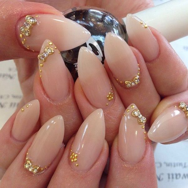 Elegant Almond-Shaped Nails with Soft Nude Polish and Glamorous Gold Accents.