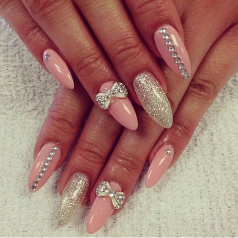 Chic Soft Pink Nail Design with Glitter Accents and Rhinestone Bow Detail.