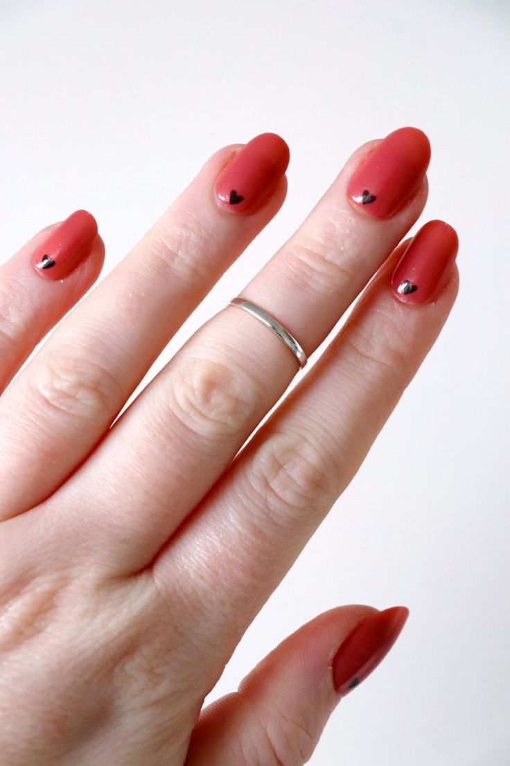 Charming Matte Red Nail Design with Delicate Black Heart Accents