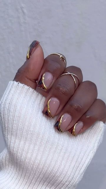 Chic Nude Nail Design Enhanced with Artistic Gold Lines and Minimalistic Rings.