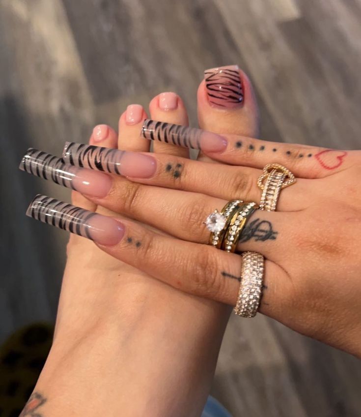 Striking Black and White Striped Acrylic Nail Design Enhanced with Pastel Accents and Elegant Rings.